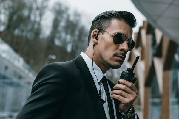 A man in a suit and tie is talking on a walkie talkie.