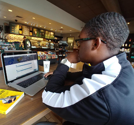 A man is sitting at a table using a laptop computer