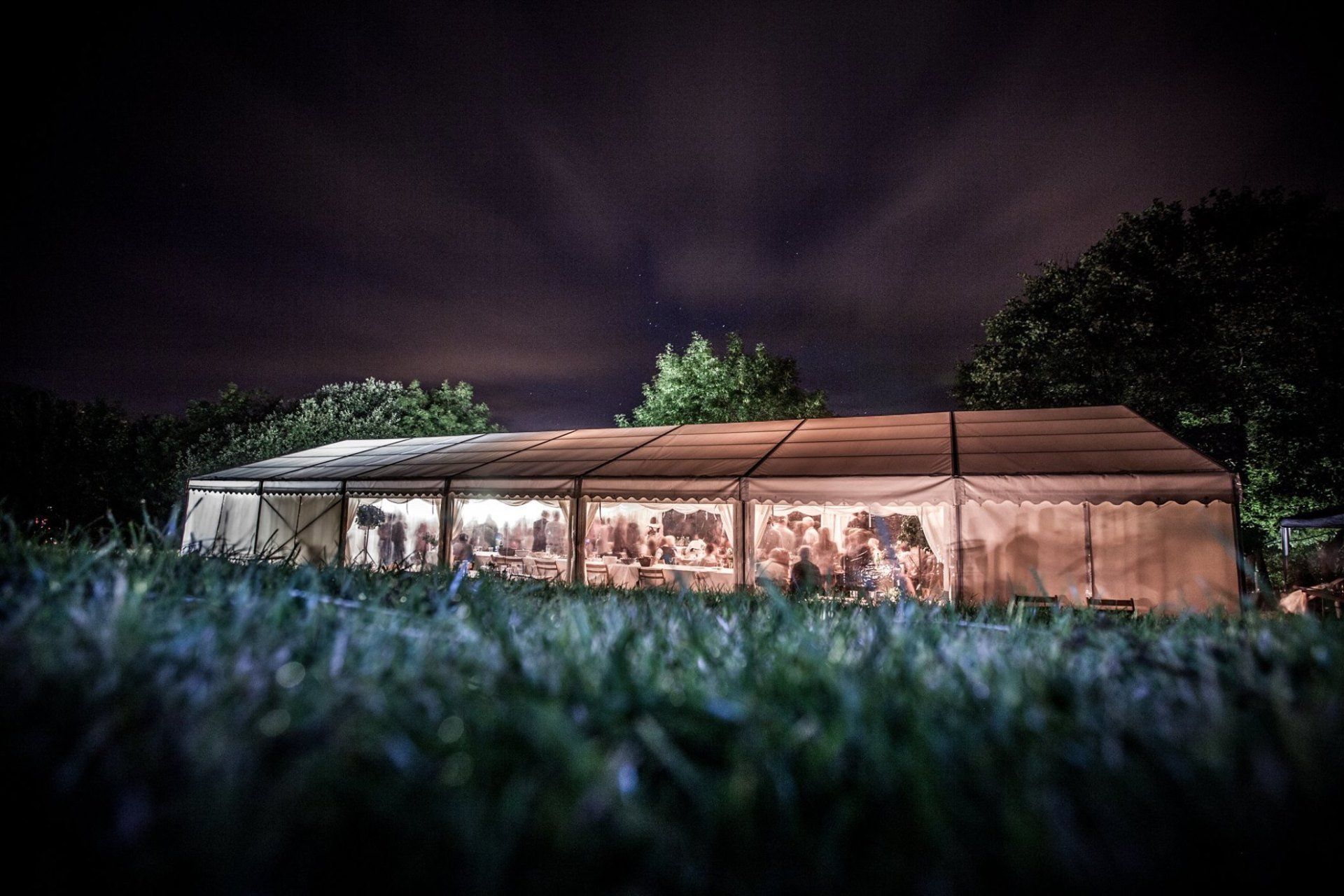A large tent is lit up at night in a field.