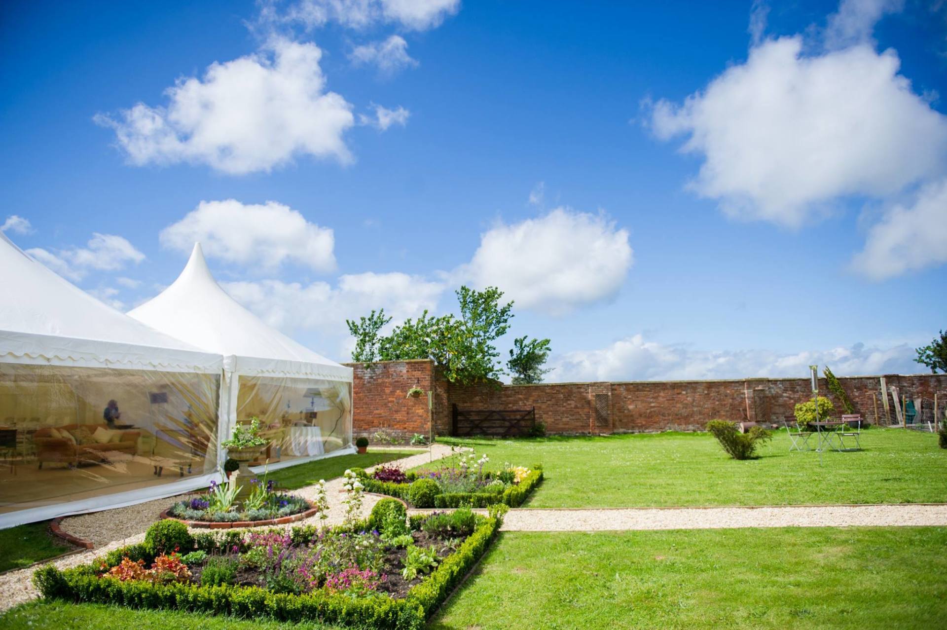 A large white tent is sitting in the middle of a lush green field.