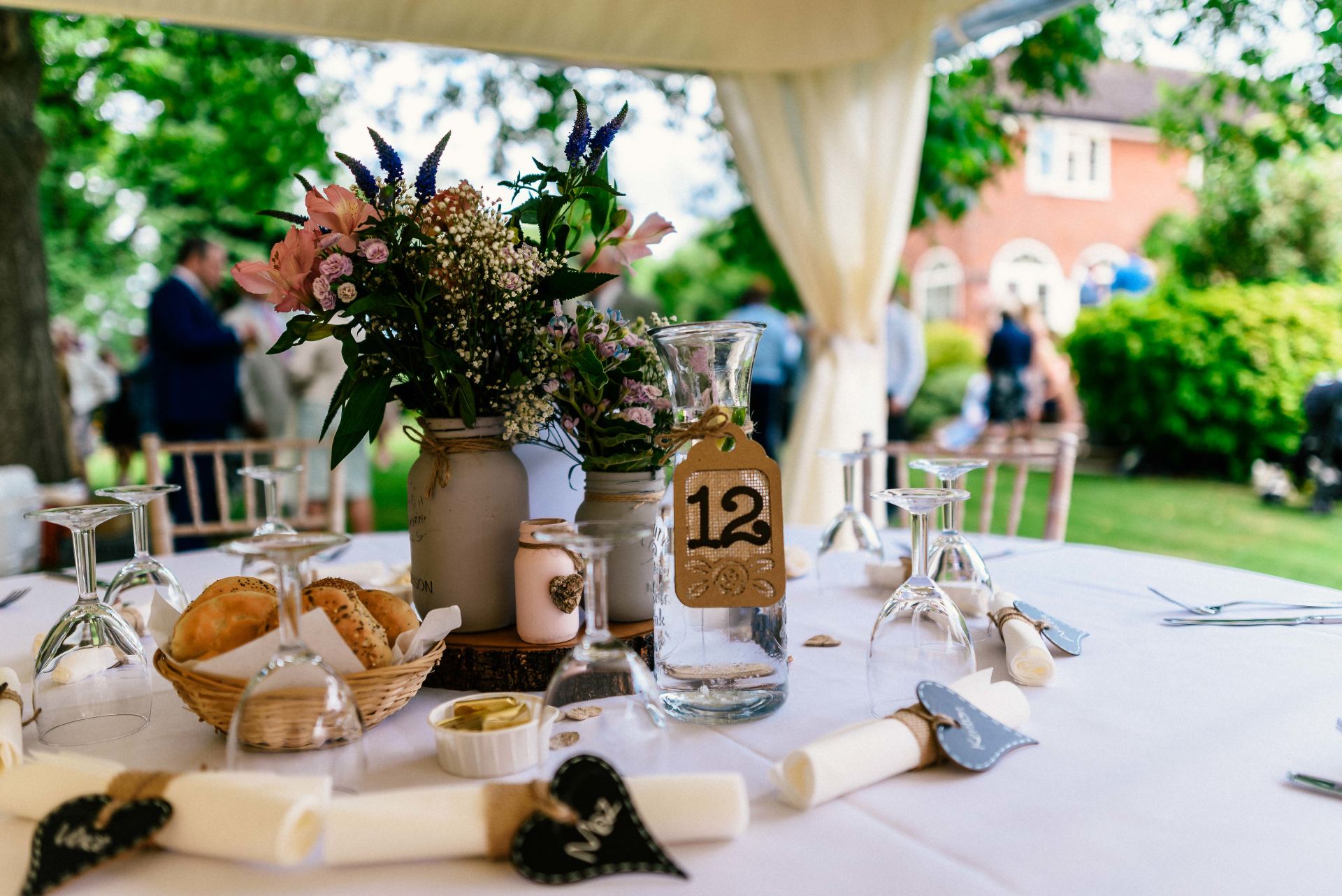 A table set for a wedding reception with a vase of flowers on it.