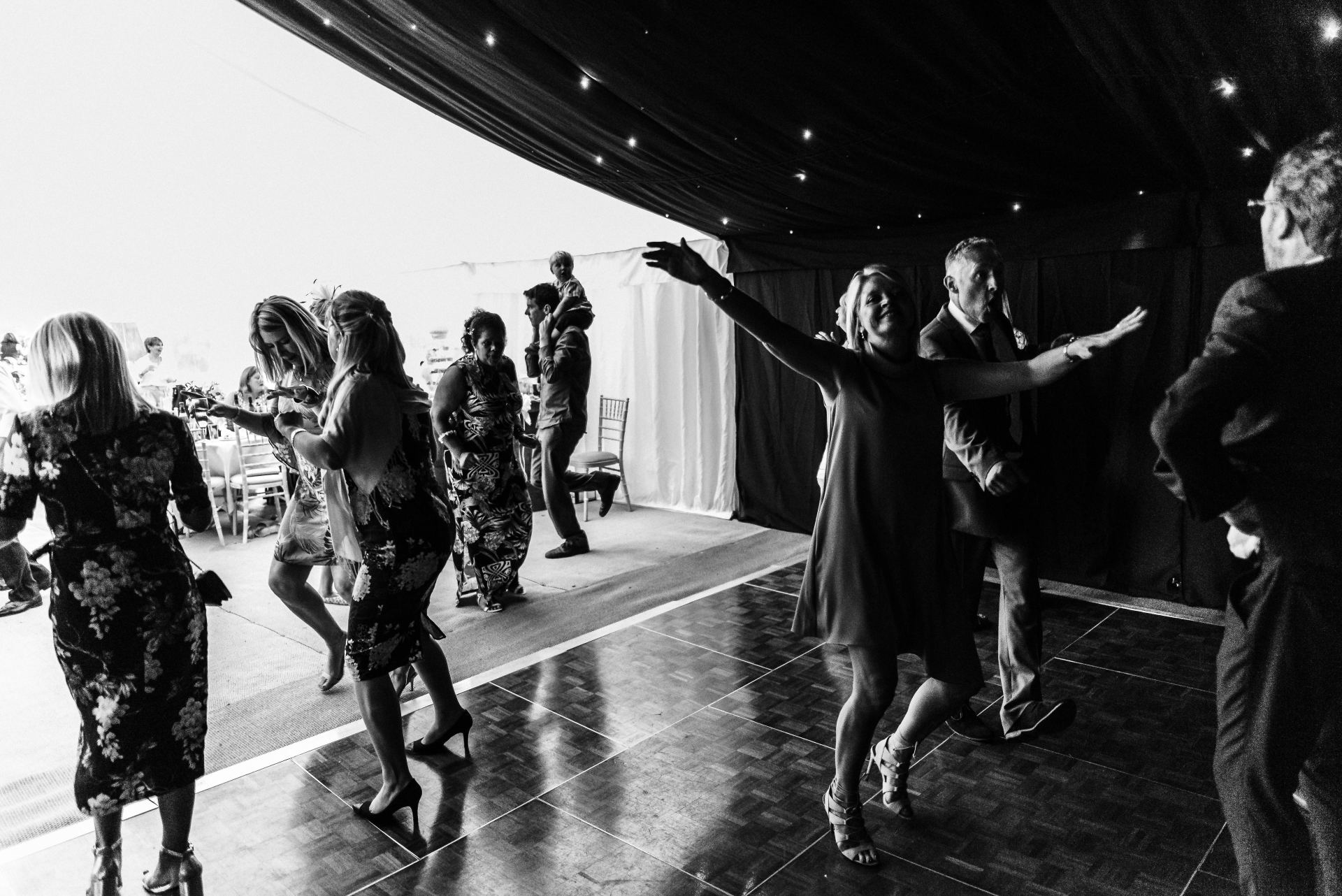 A group of people are dancing on a dance floor in a black and white photo.