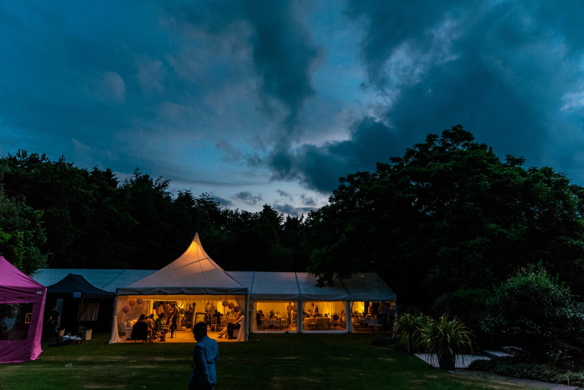 A man is standing in front of a tent lit up at night.