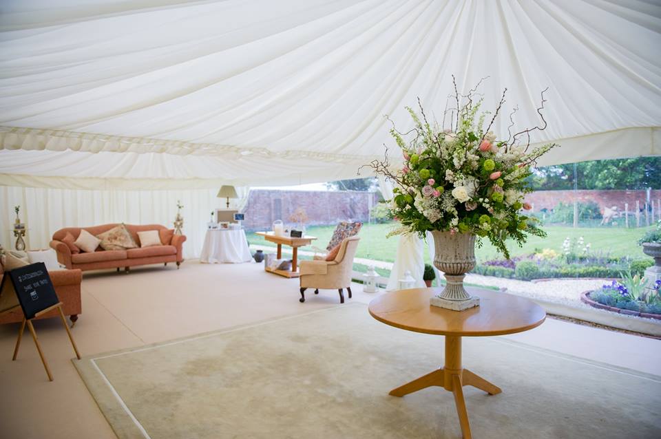 A table with a vase of flowers on it in a tent.
