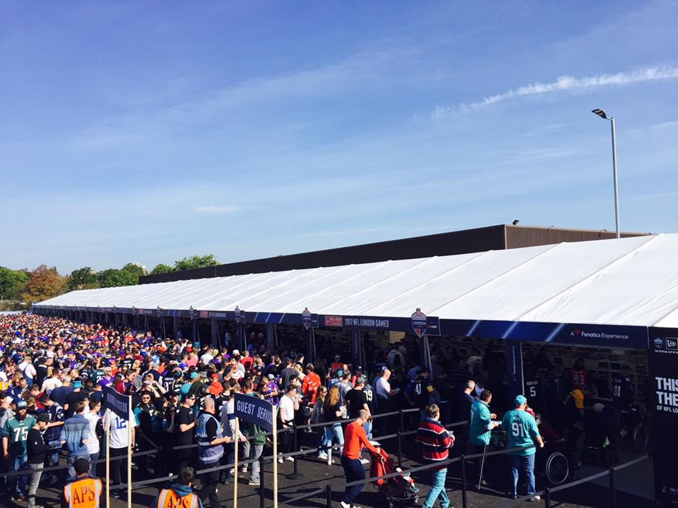 A large crowd of people are gathered under a white tent.