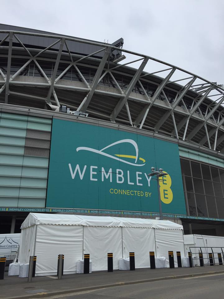 A large green sign on the side of a building that says wembley connected by b
