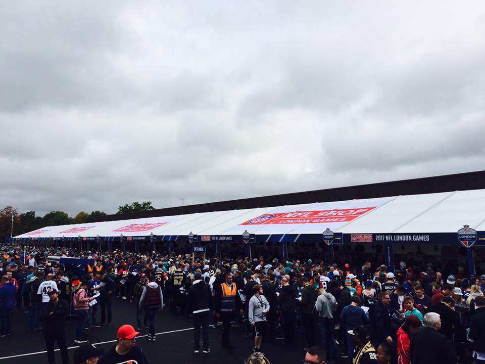 A large crowd of people are gathered in front of a building with a sign that says ' coca cola ' on it
