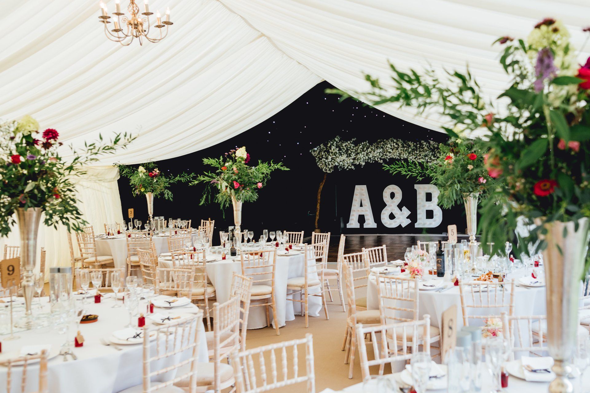 A large tent with tables and chairs set up for a wedding reception.