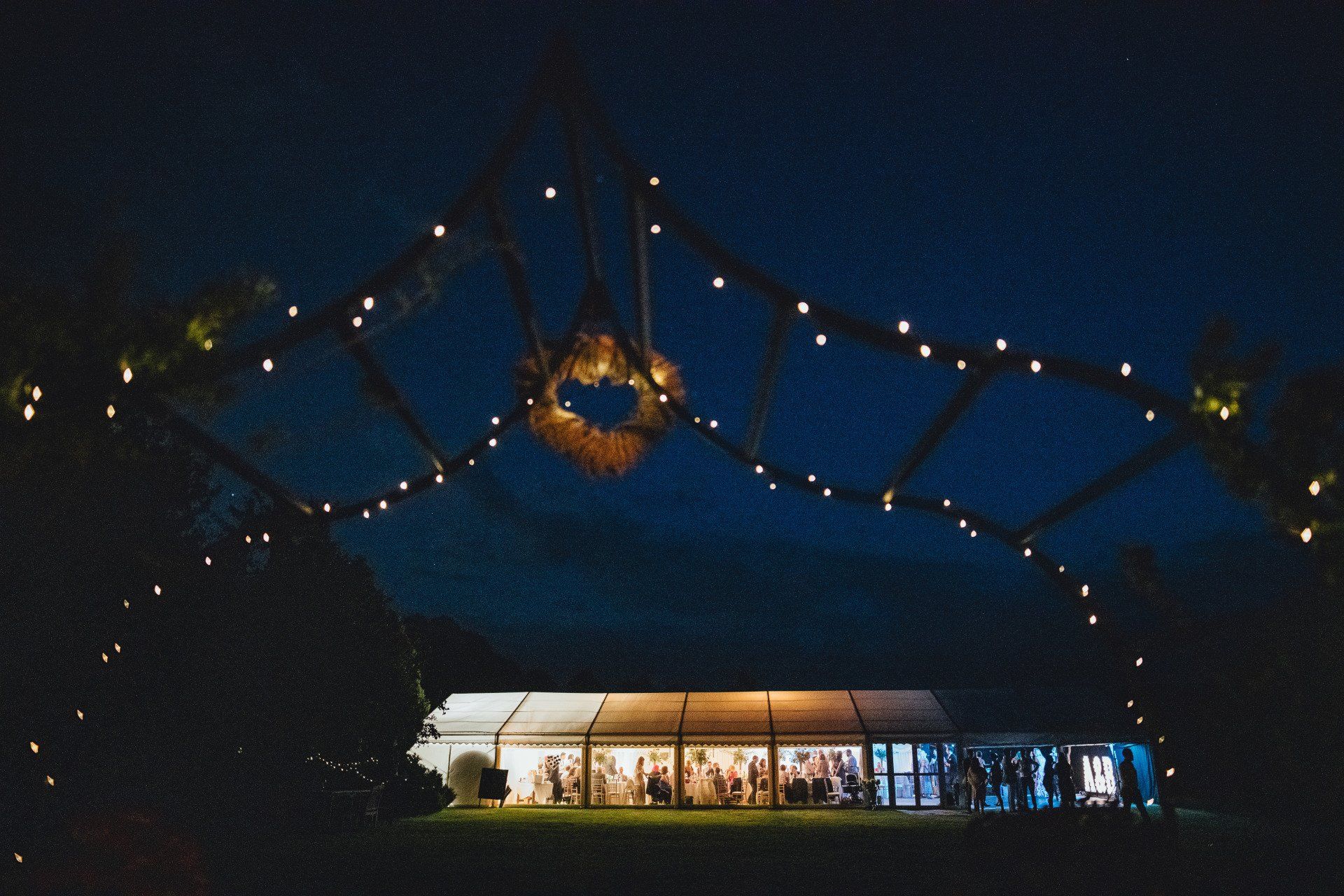 A tent is lit up at night with lights hanging from the ceiling