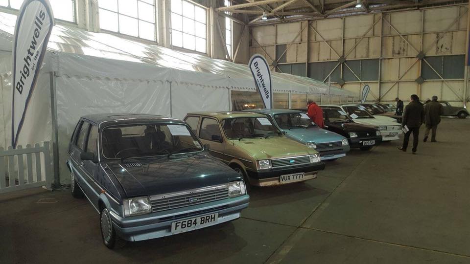 A row of cars are parked in a warehouse.