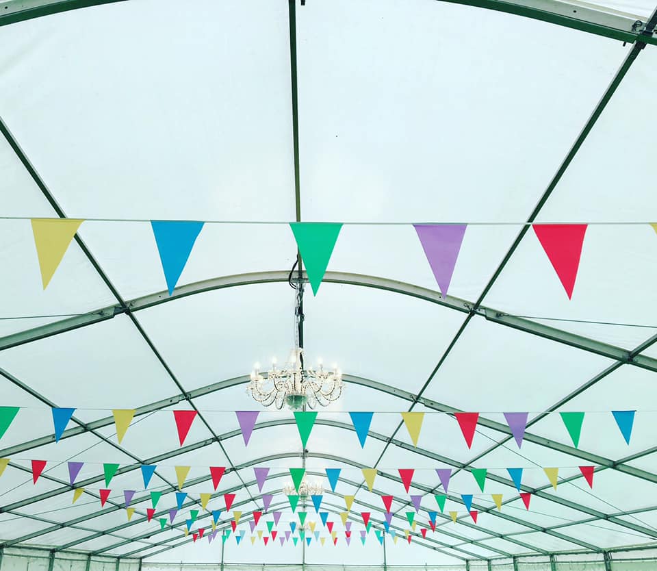 A bunch of colorful flags are hanging from the ceiling of a tent