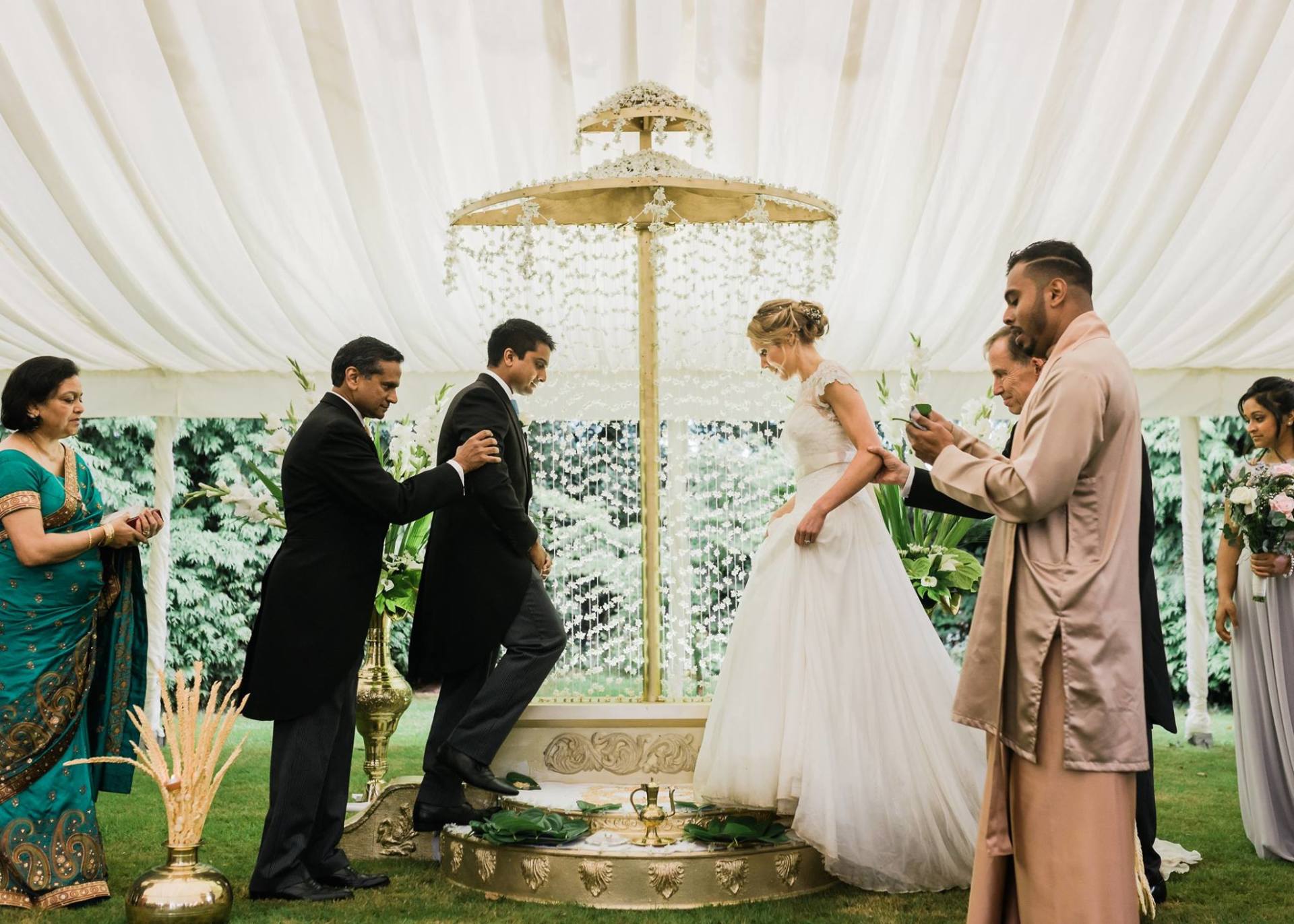 A group of people are standing around a bride and groom at a wedding ceremony.