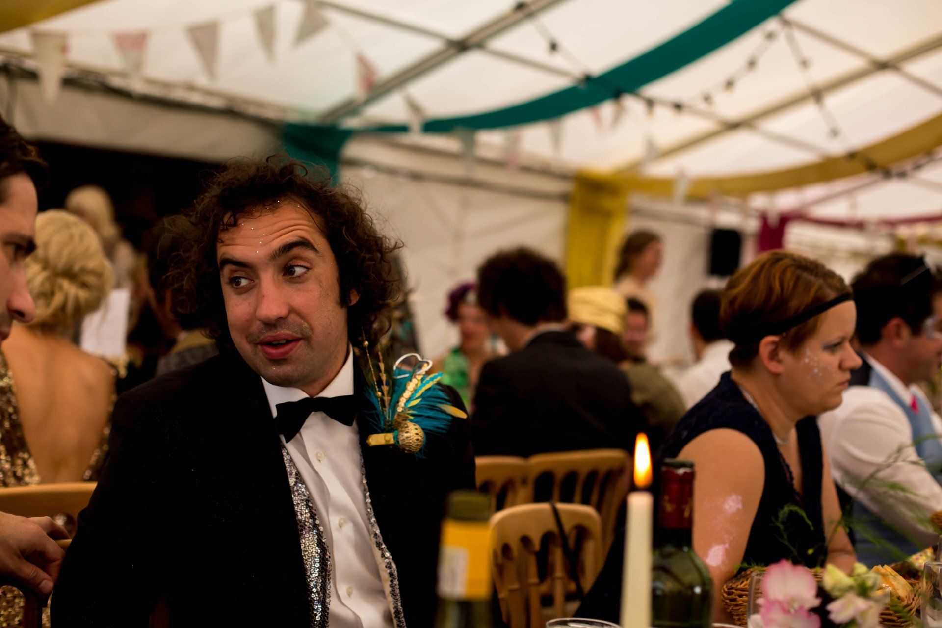 A man in a tuxedo is sitting at a table at a party.