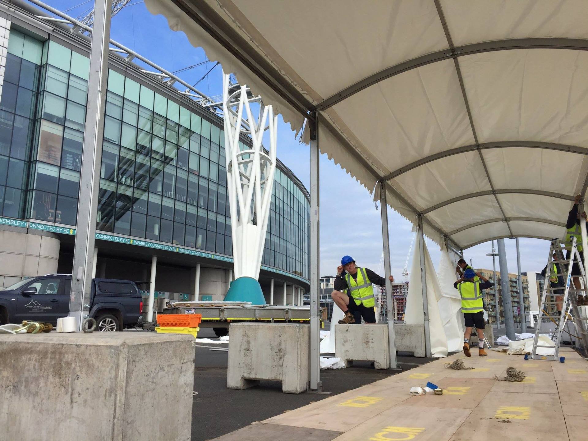 A group of construction workers are working on a large white tent.