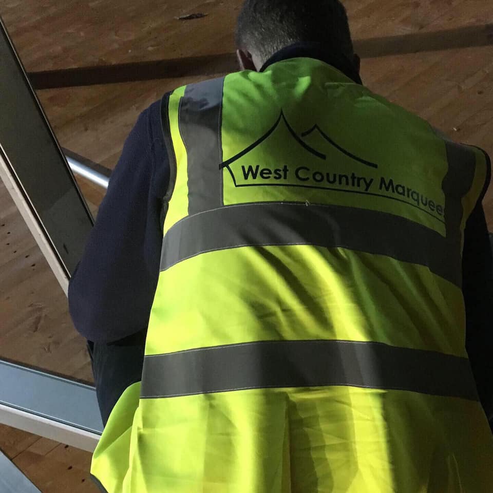 A man wearing a yellow vest that says west country marquee