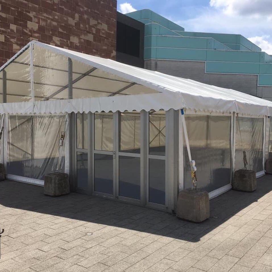 A large white tent is sitting in front of a building