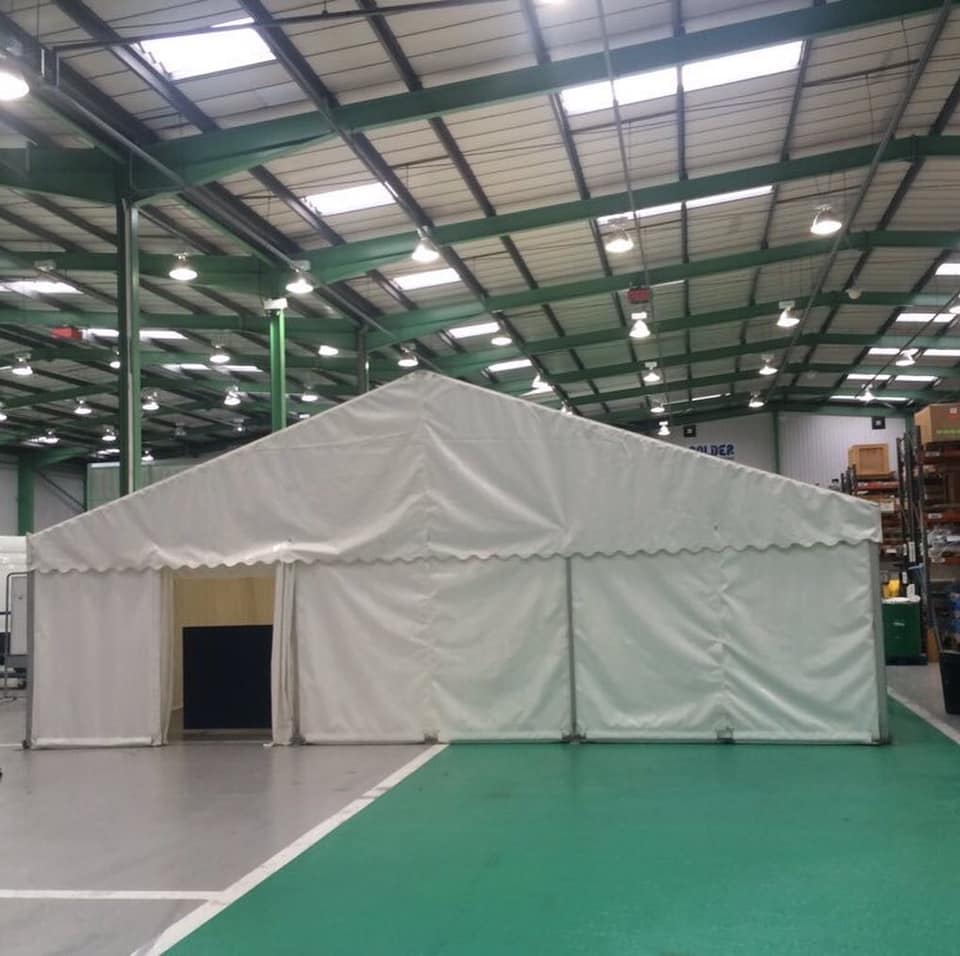 A large white tent is in the middle of a large warehouse