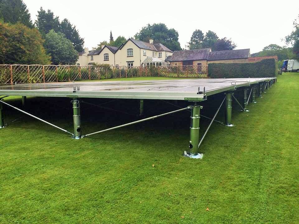 A large stage is sitting in the middle of a lush green field.