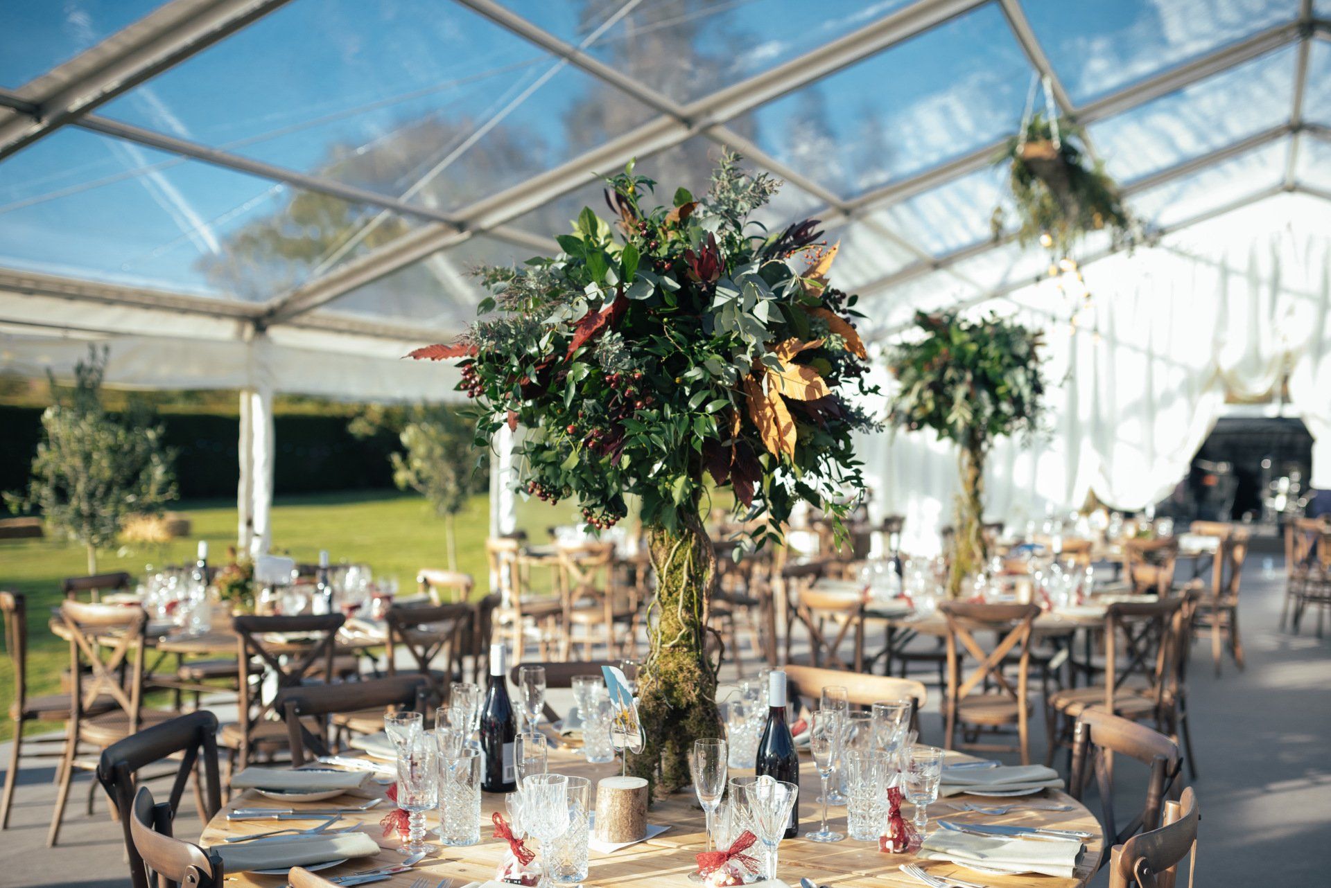 A table set for a wedding reception under a clear tent.