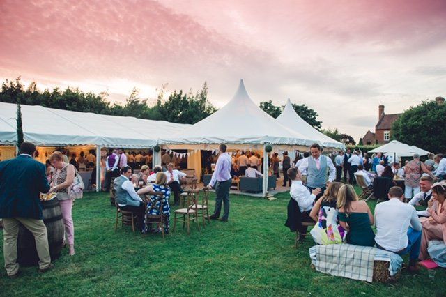 A group of people are sitting under tents in a field.
