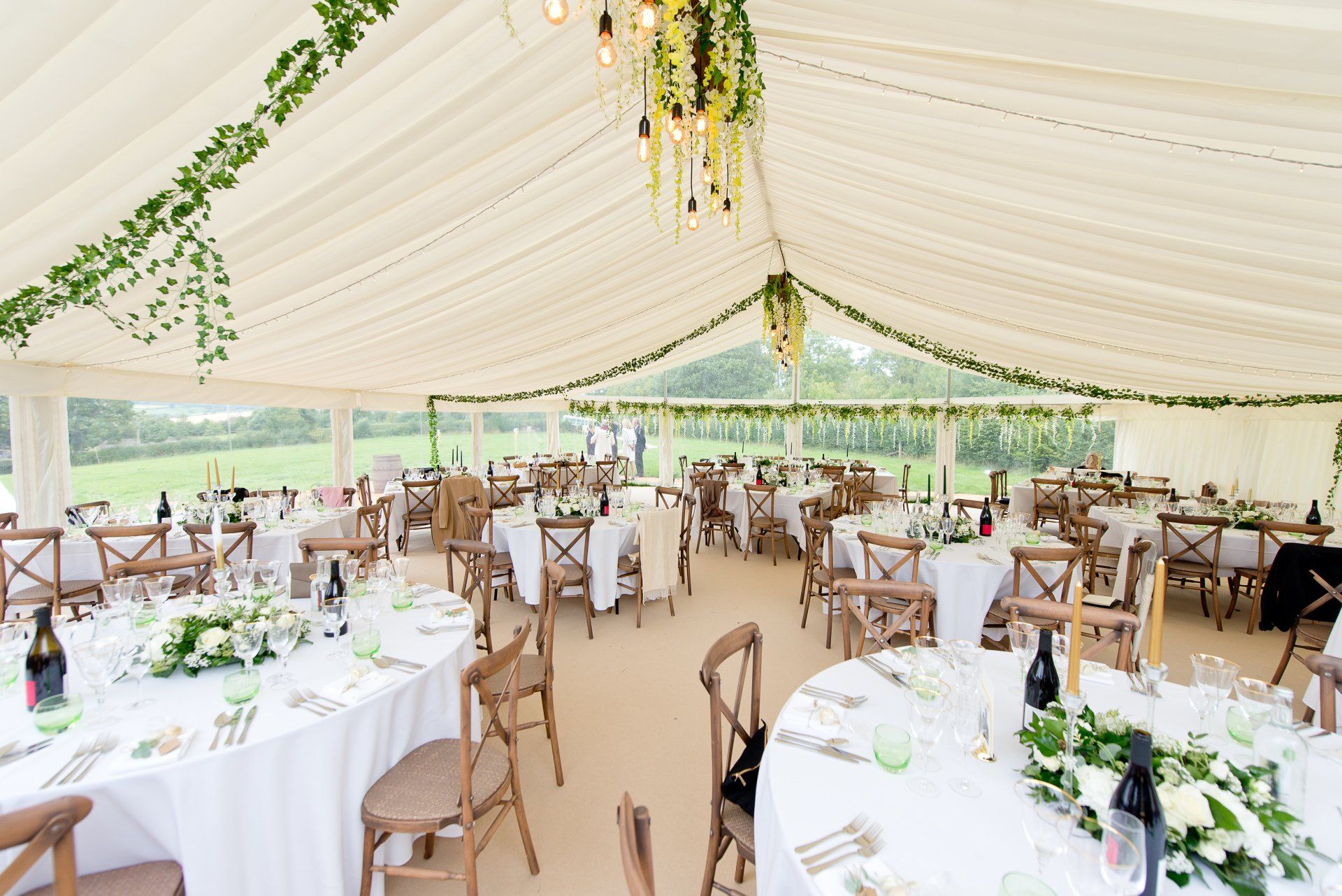 A large tent with tables and chairs set up for a wedding reception.