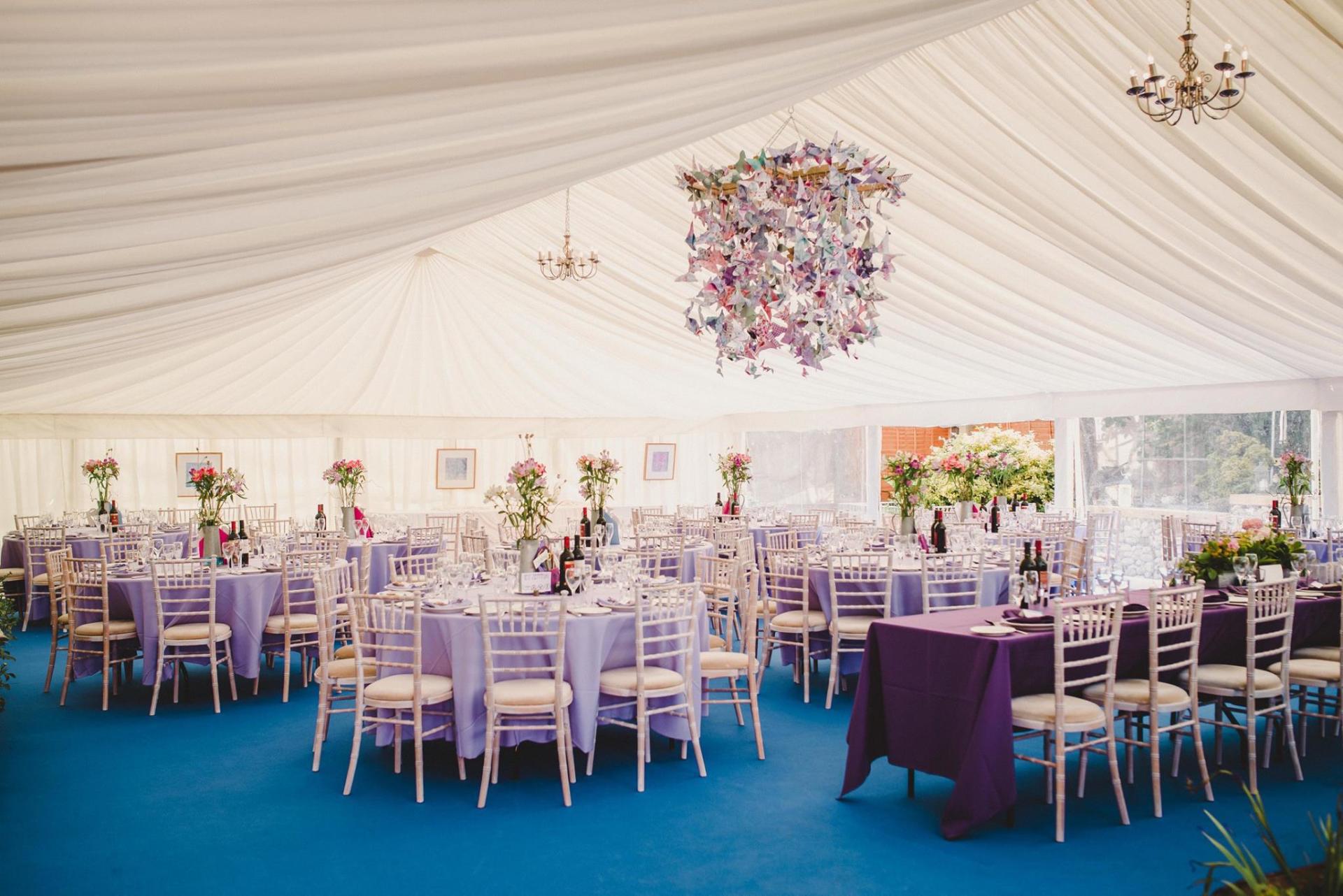 A large tent with tables and chairs set up for a wedding reception.