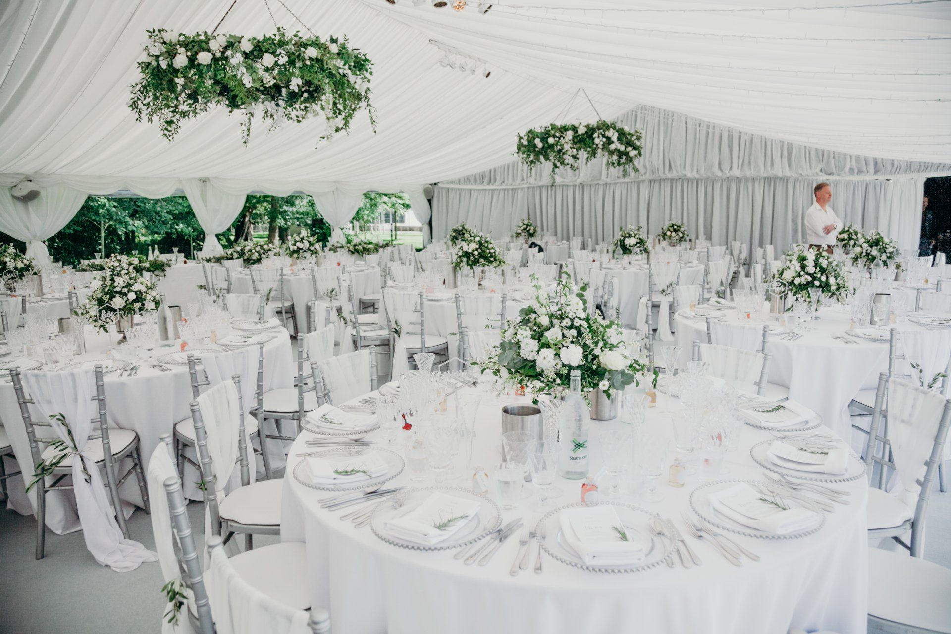 A large white tent with tables and chairs set up for a wedding reception.