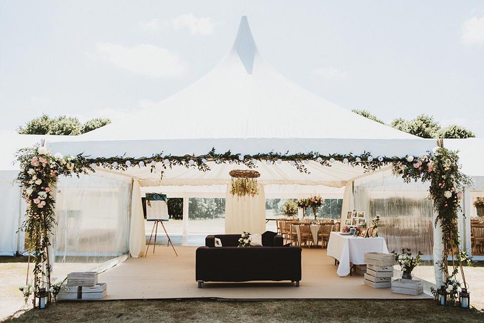 A white tent with a couch and tables underneath it.