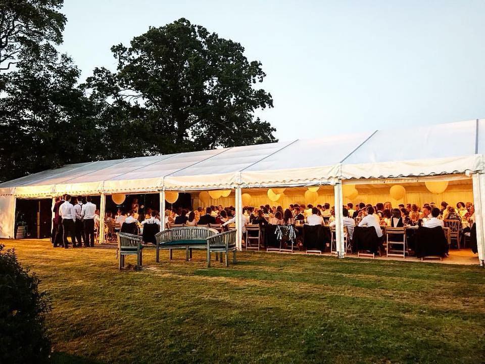A group of people are sitting at tables under a tent.