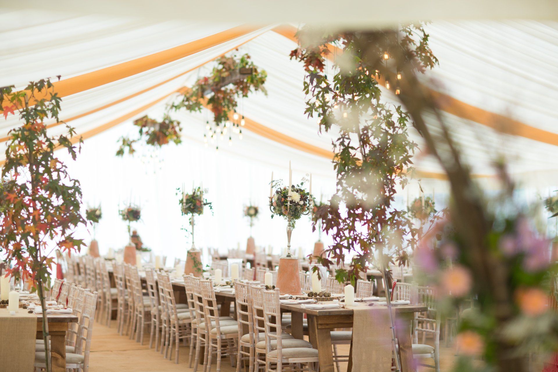 A large tent with tables and chairs set up for a wedding reception.