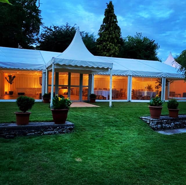 A large white tent is sitting in the middle of a lush green field