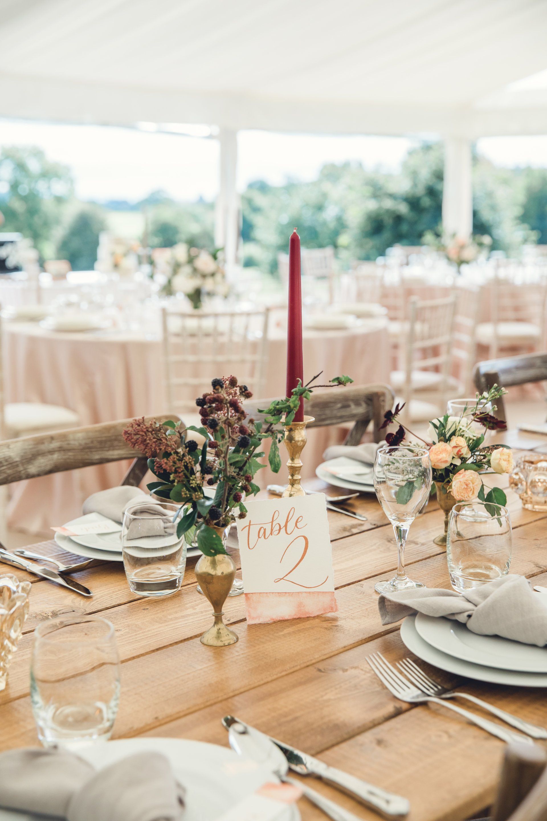 A table set for a wedding reception with plates , utensils , candles and flowers.