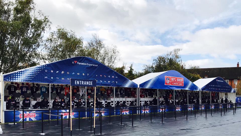 A row of blue and white tents are lined up in a parking lot.