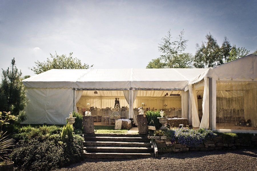 A large white tent is sitting in the middle of a garden.