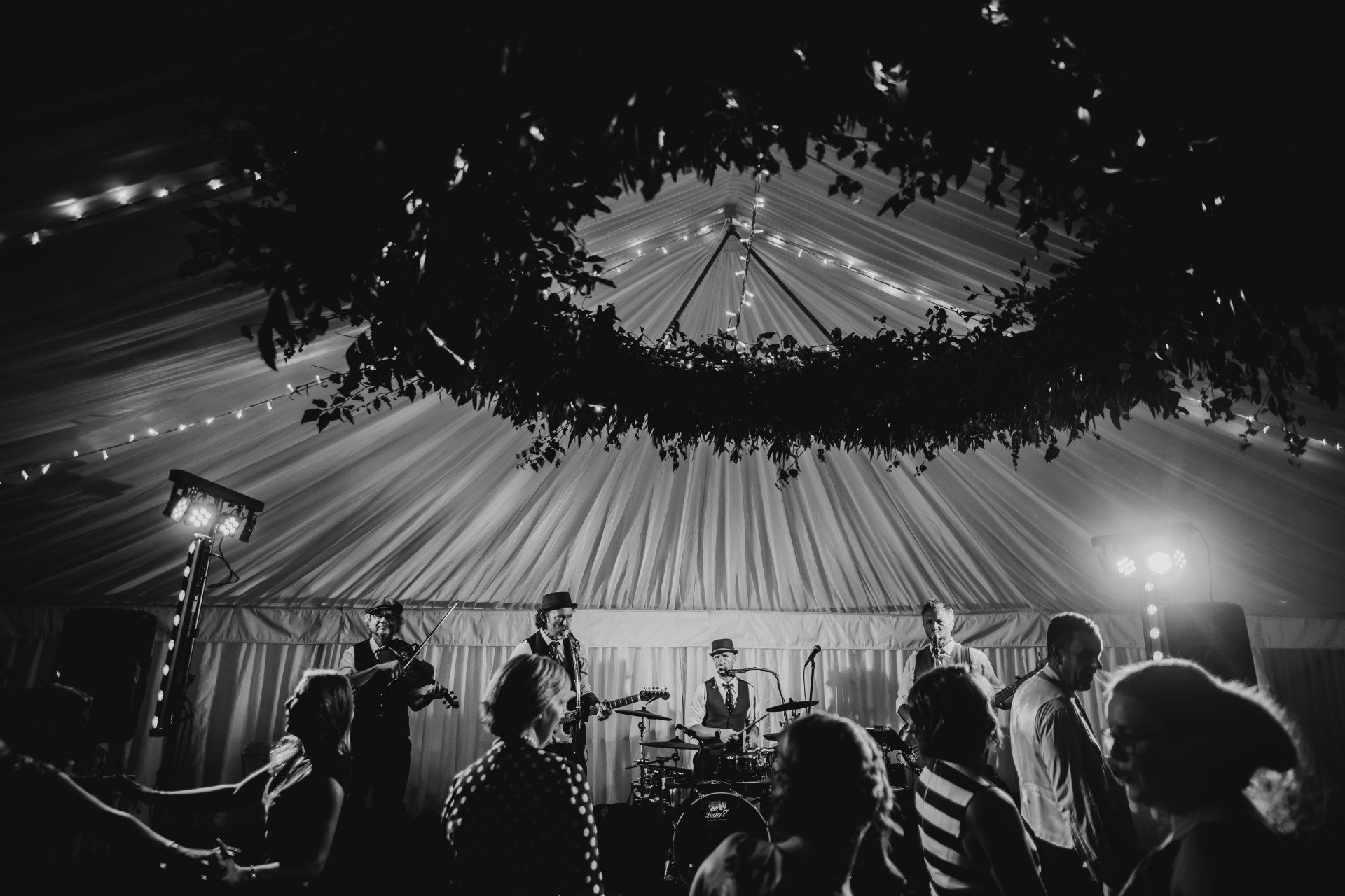 A black and white photo of a group of people dancing in a tent.
