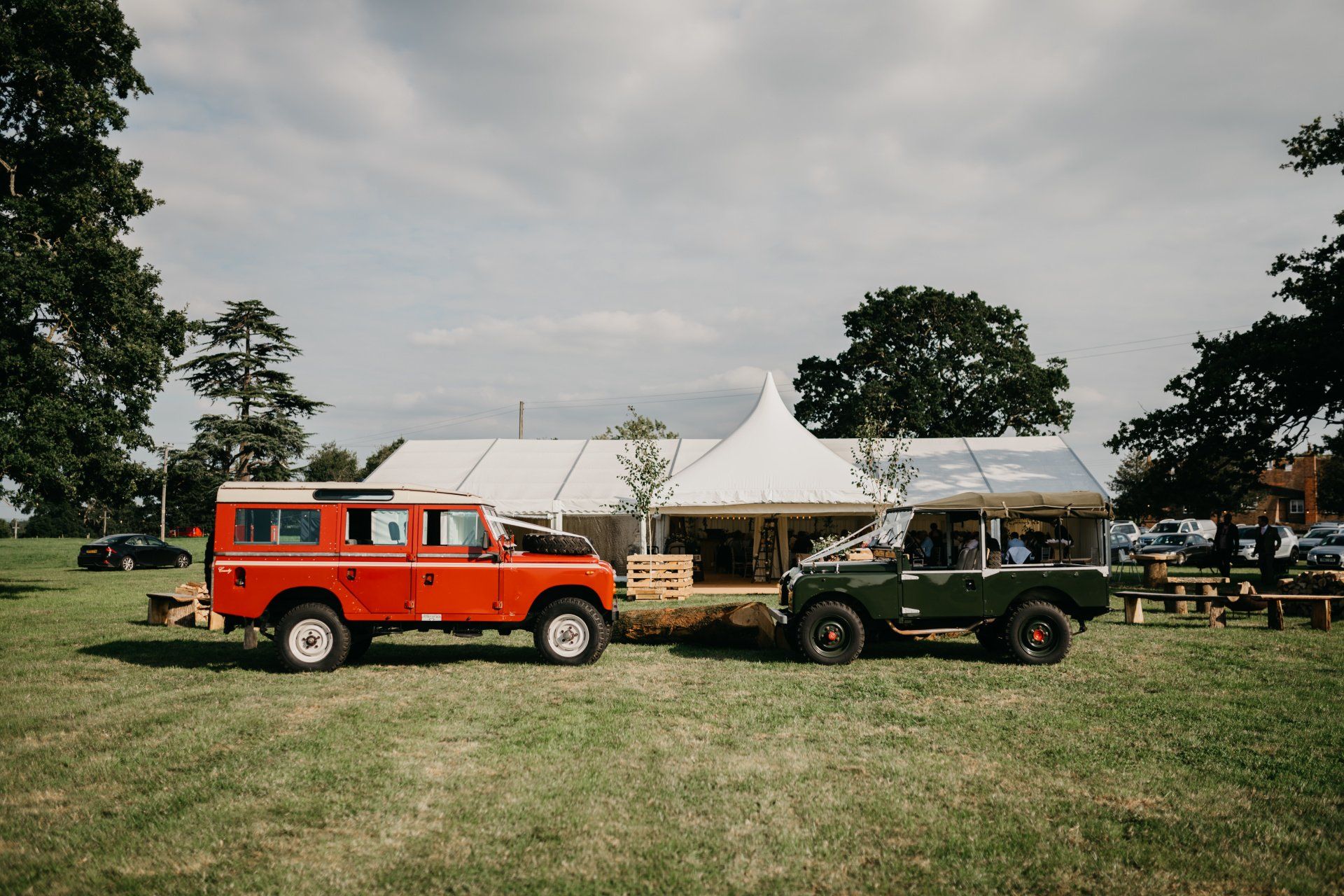 Two land rovers are parked next to each other in a field.