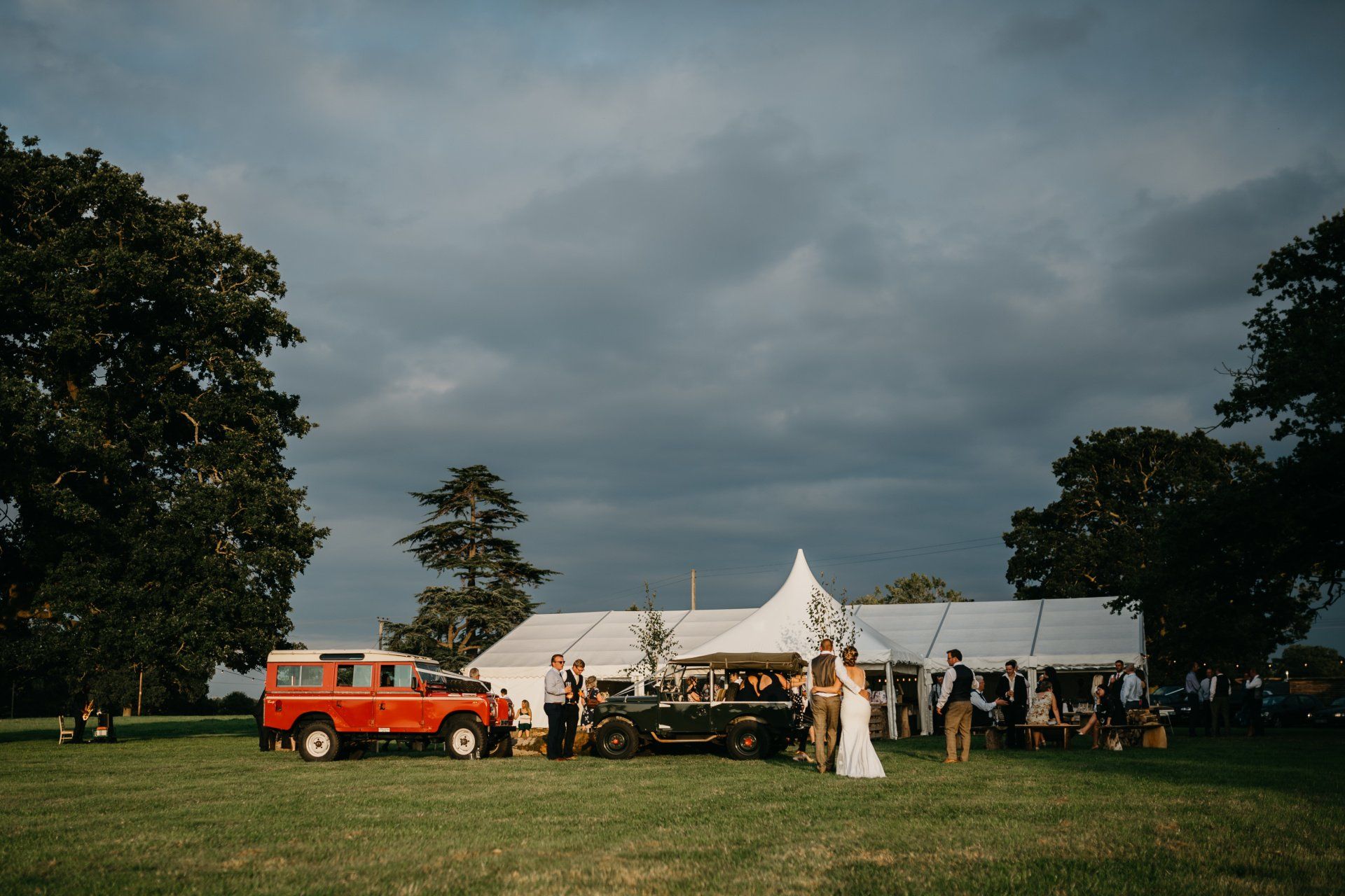 A bride and groom are standing in front of a tent in a field.