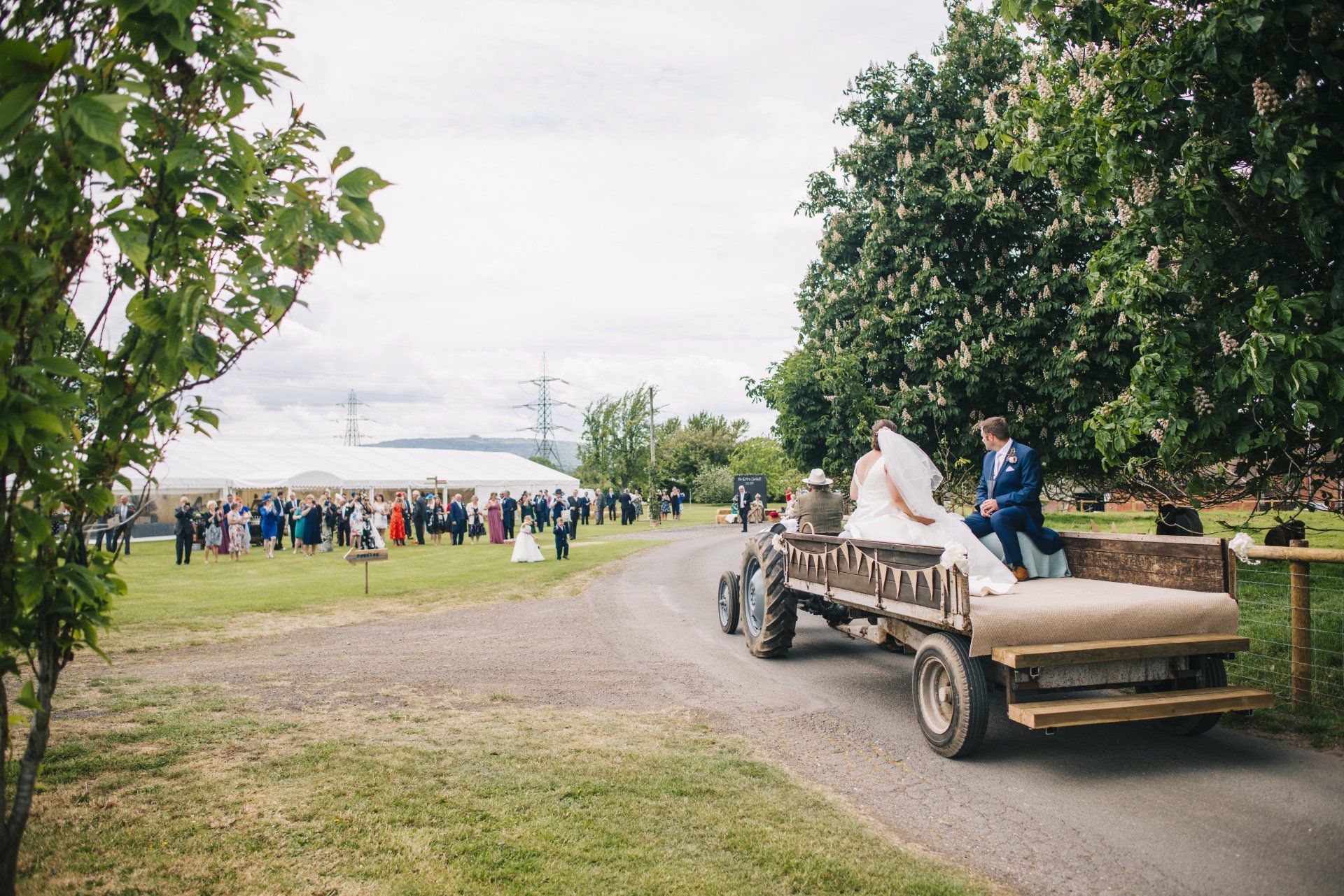 A bride and groom are riding on the back of a horse drawn carriage.