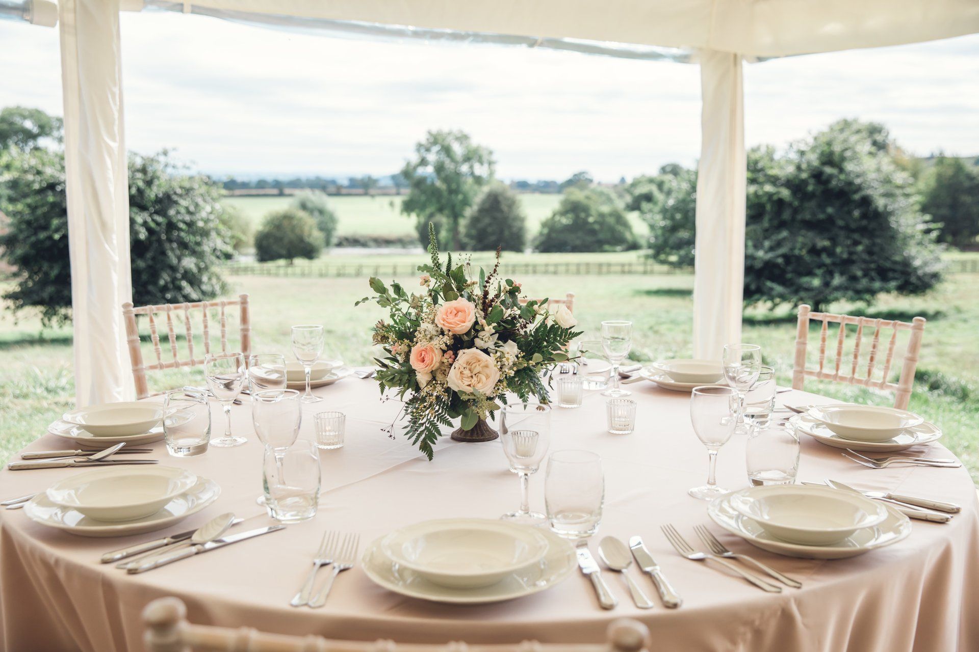 A table set for a wedding reception with a vase of flowers on it.