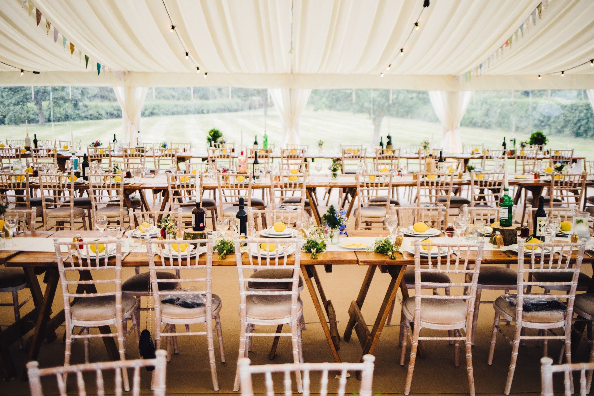 A large tent with tables and chairs set up for a wedding reception.
