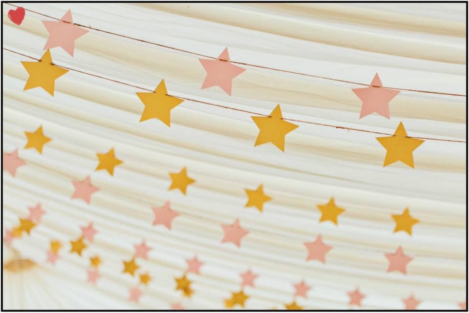 A string of pink and yellow stars on a white cloth
