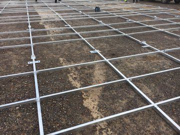 A grid of metal frames sitting on top of a dirt ground.