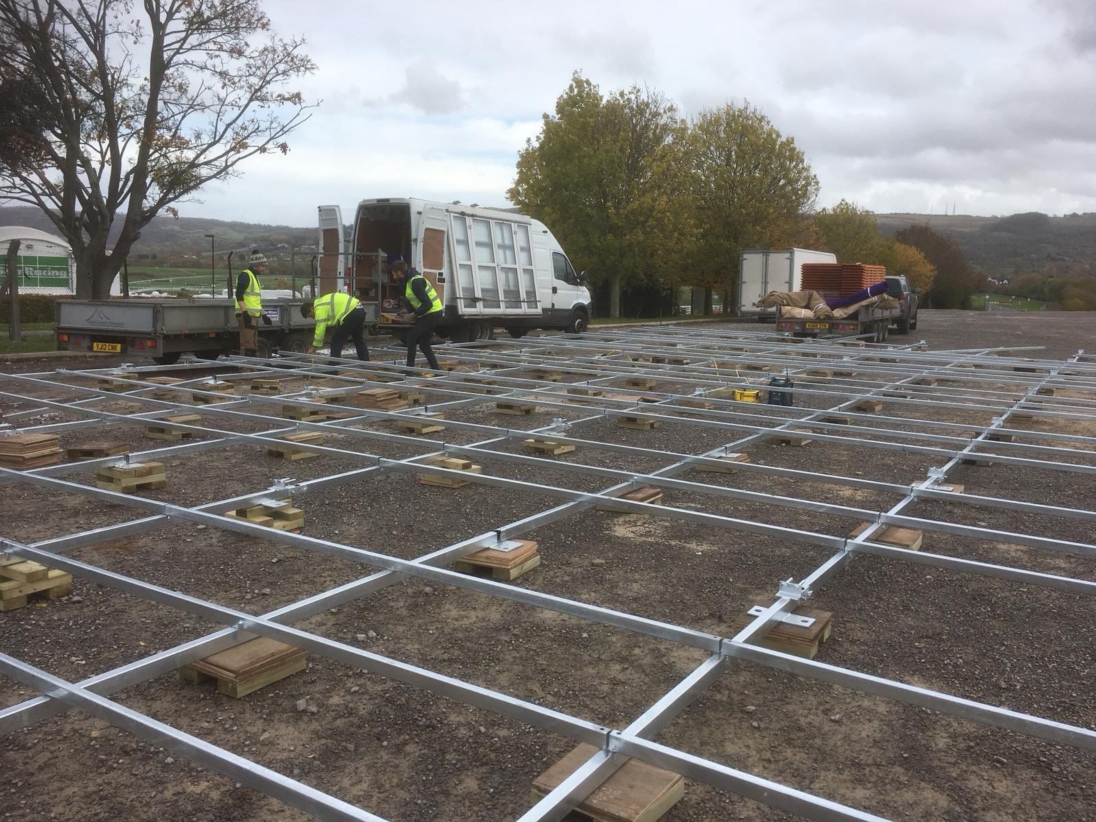 A group of people are working on a solar panel installation in a parking lot.