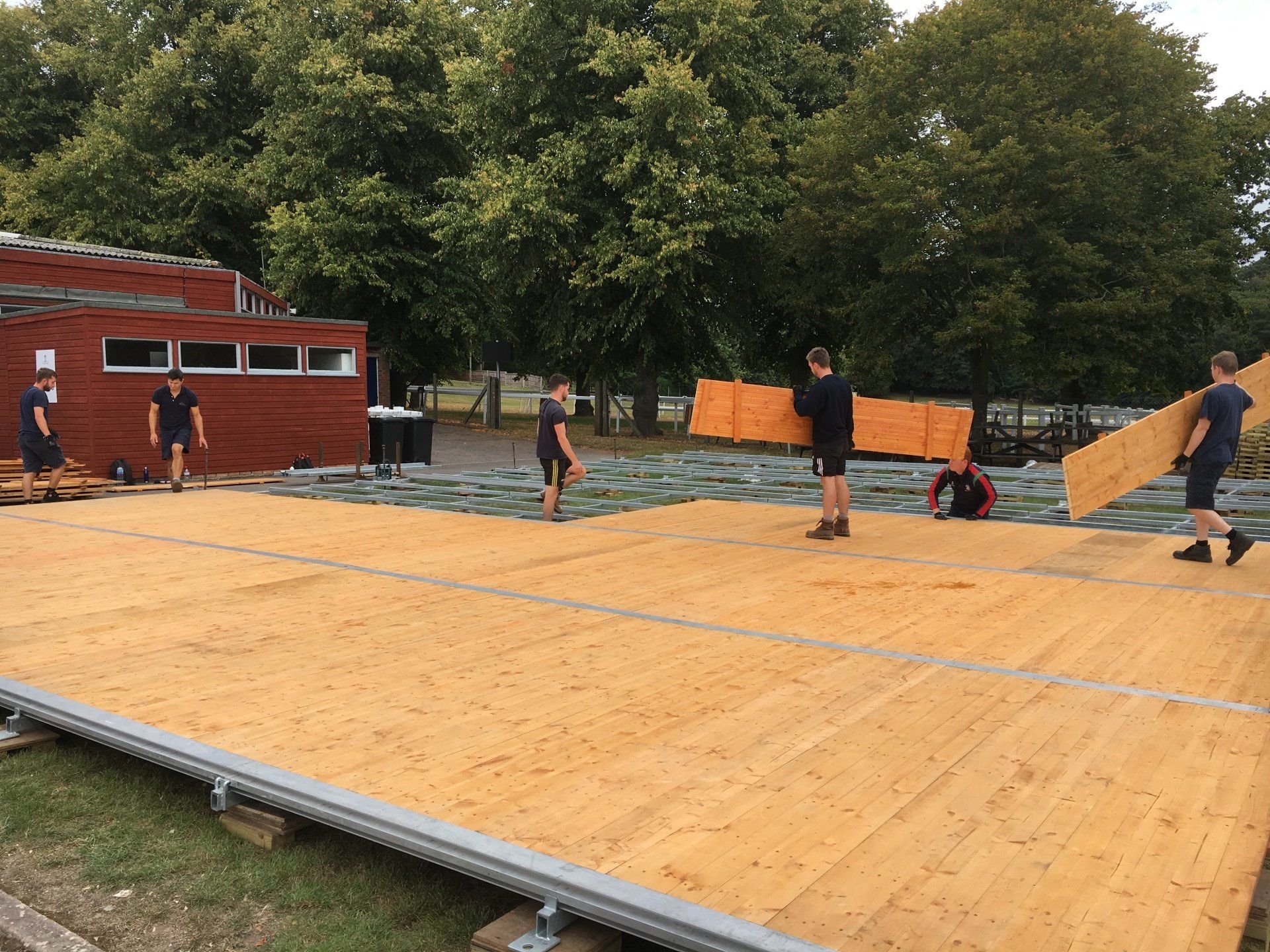 A group of people are working on a wooden stage.