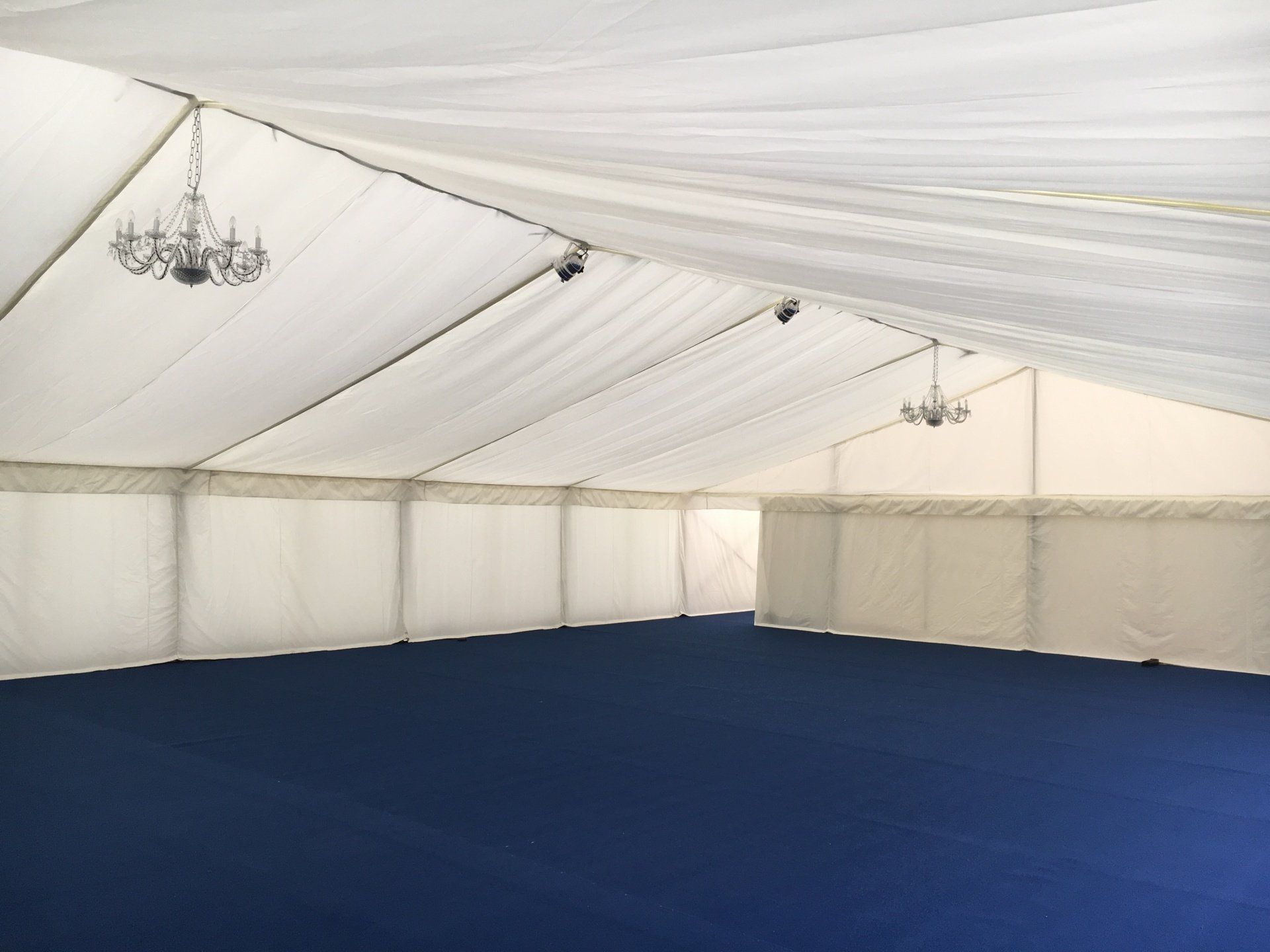 A large empty tent with blue carpet and a white ceiling.