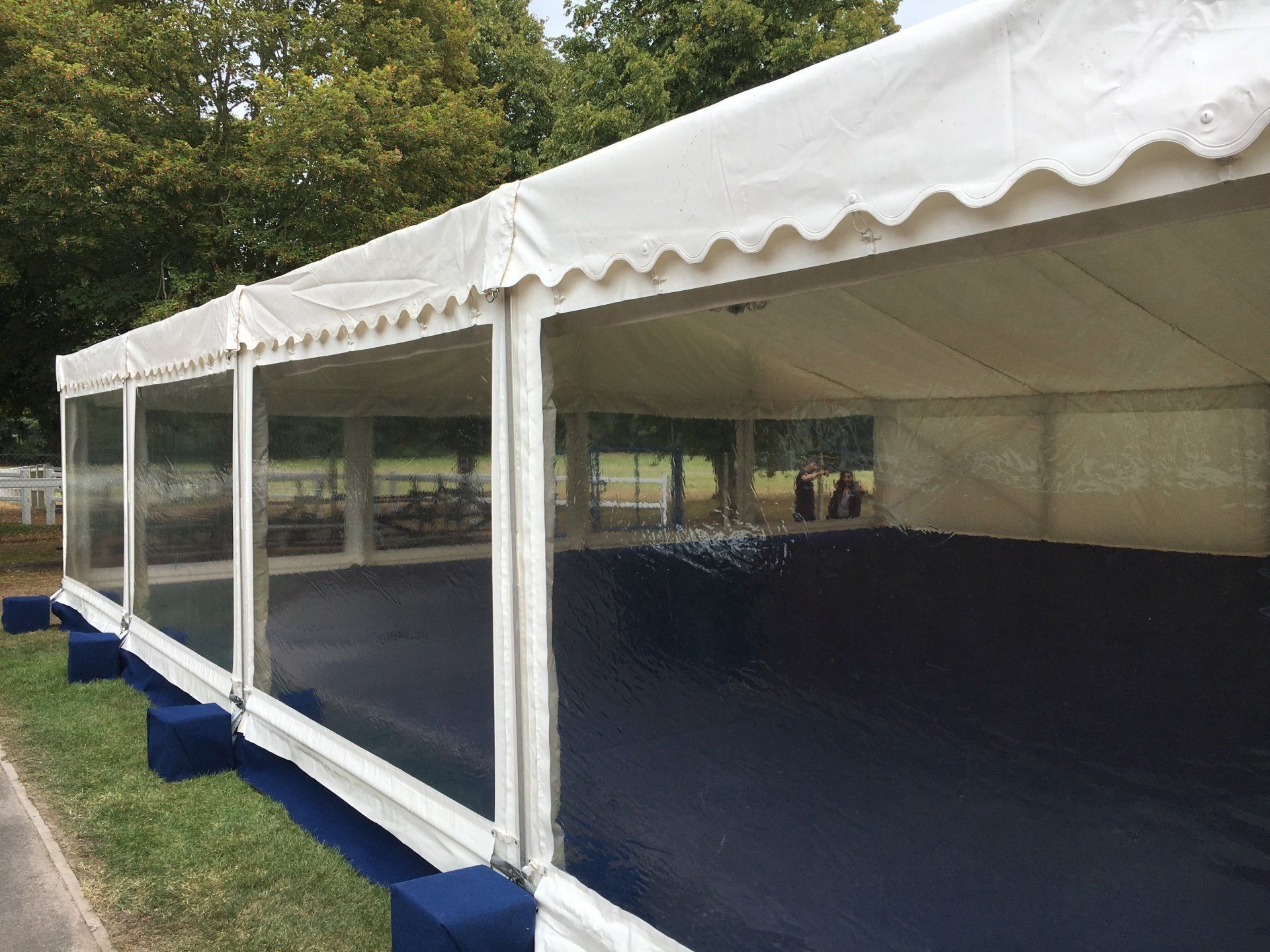 A large white tent with clear windows is sitting on top of a lush green field.