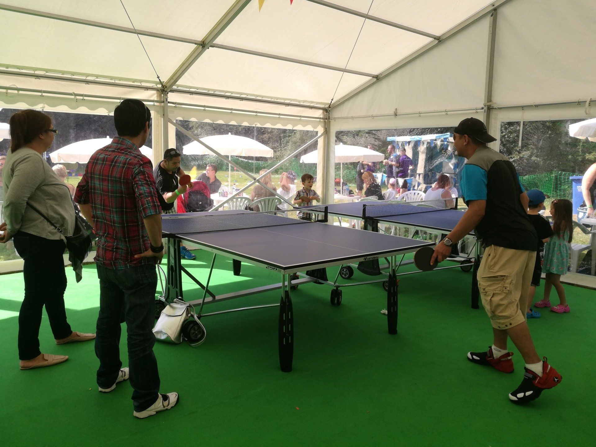 A group of people are playing ping pong in a tent