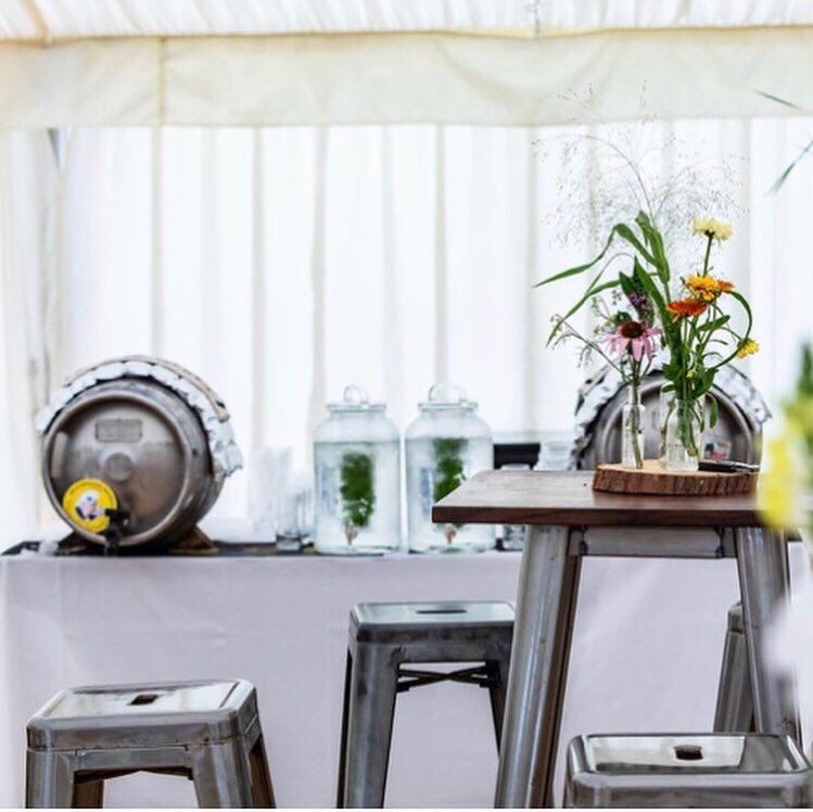 A table with a barrel on it and a vase of flowers on it
