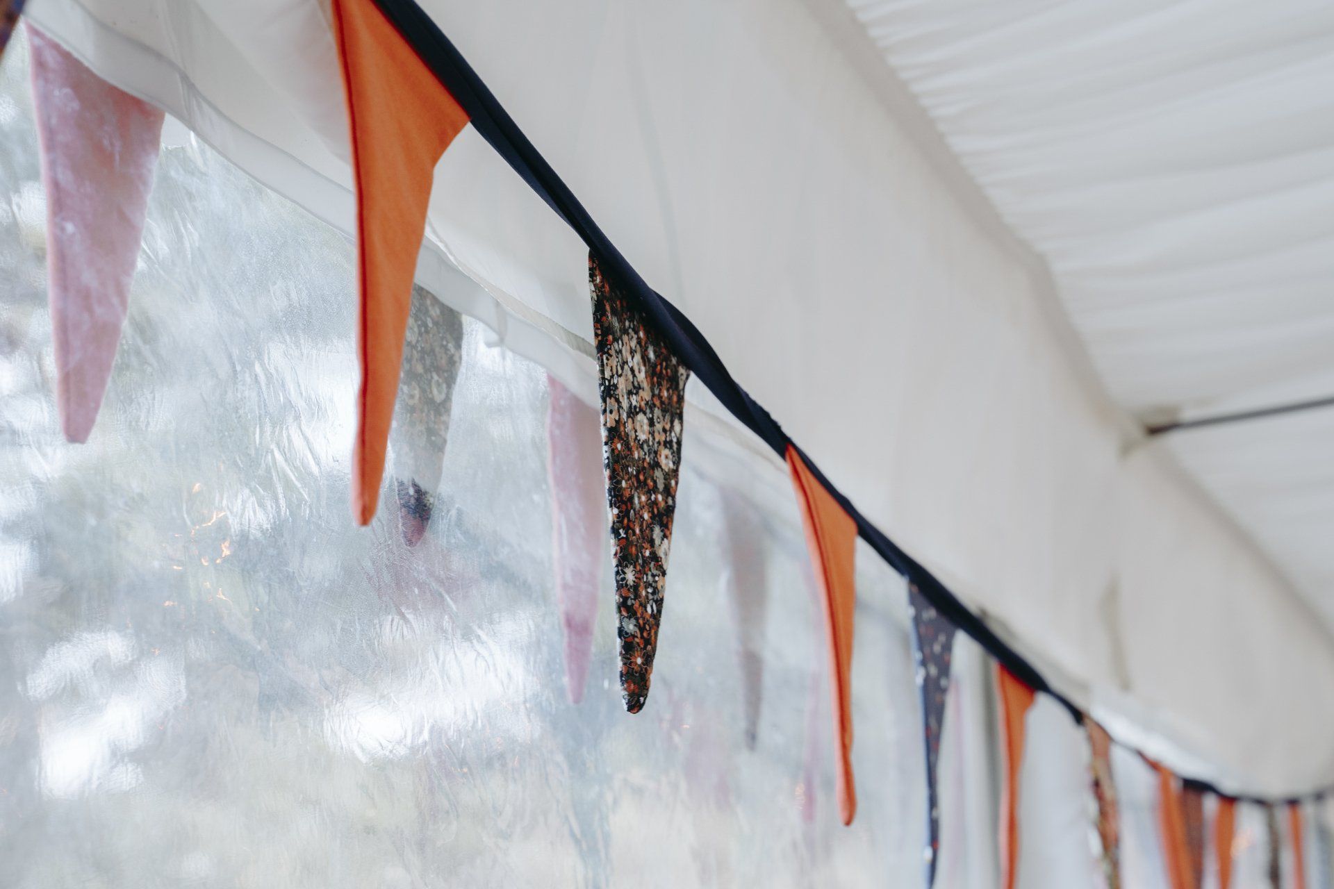 A bunch of flags are hanging from the ceiling of a tent.