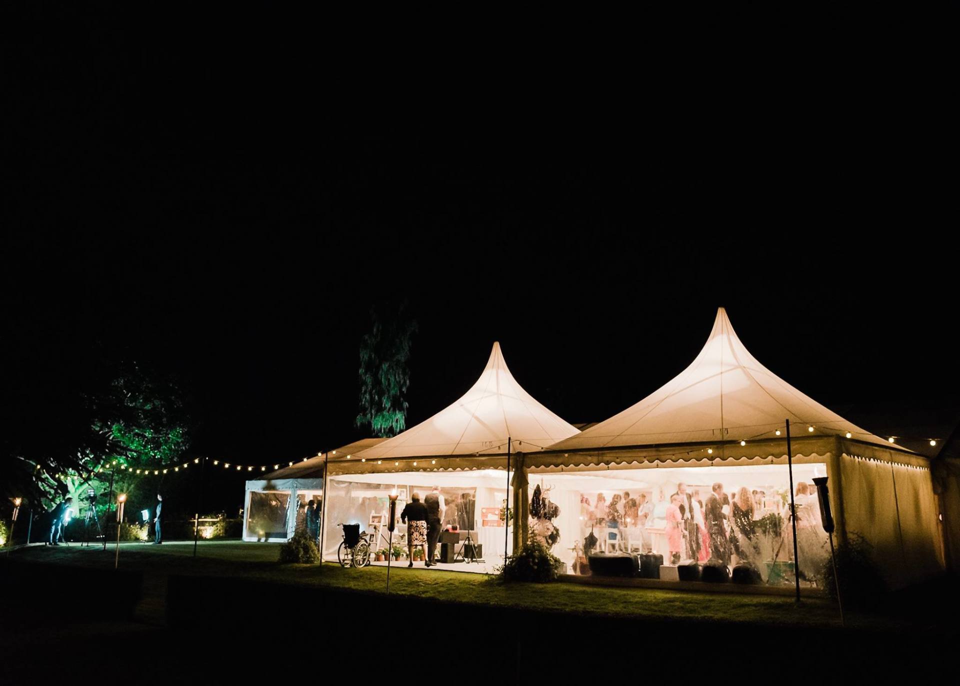 A couple of tents are lit up at night.